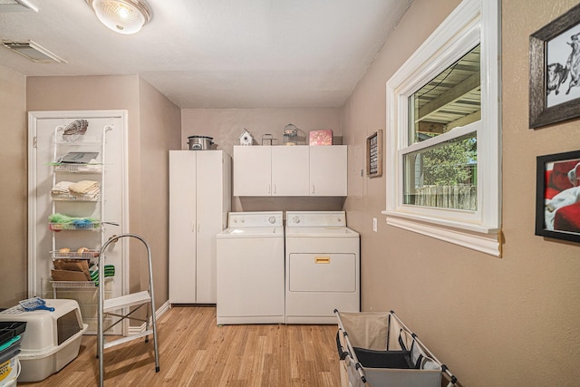 504 Harrison Ln, Hurst, TX 76053 - laundry room with cabinet space, separate washer and dryer, and light wood-style flooring