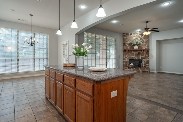 4748 Mcbreyer Pl, Fort Worth, TX 76244 - kitchen featuring a center island, a fireplace, brown cabinetry, a ceiling fan, and arched walkways