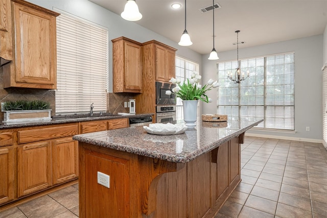 4748 Mcbreyer Pl, Fort Worth, TX 76244 - kitchen with appliances with stainless steel finishes, light tile patterned floors, tasteful backsplash, a kitchen island, and a breakfast bar area