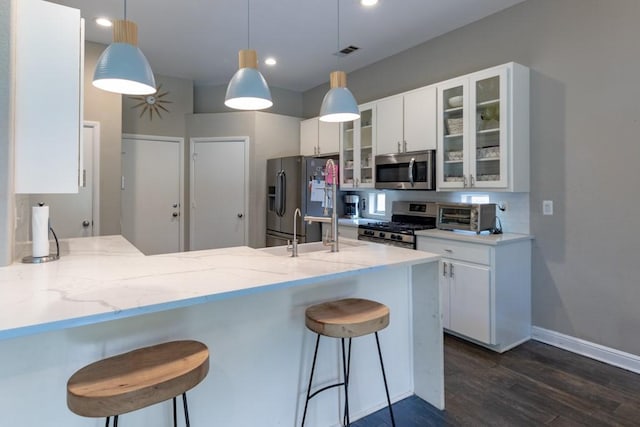 1211 Circle Ln, Bedford, TX 76022 - kitchen with appliances with stainless steel finishes, dark wood-type flooring, a peninsula, light stone countertops, and a kitchen bar