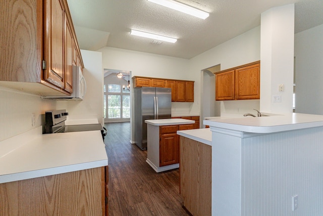 6736 Braeview Dr, Fort Worth, TX 76137 - kitchen featuring white appliances, brown cabinetry, dark wood-style floors, a peninsula, and a textured ceiling