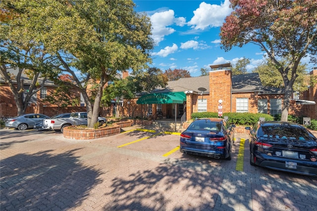 18333 Roehampton Dr Unit 513, Dallas, TX 75252 - view of front facade with uncovered parking, a chimney, brick siding, and roof with shingles