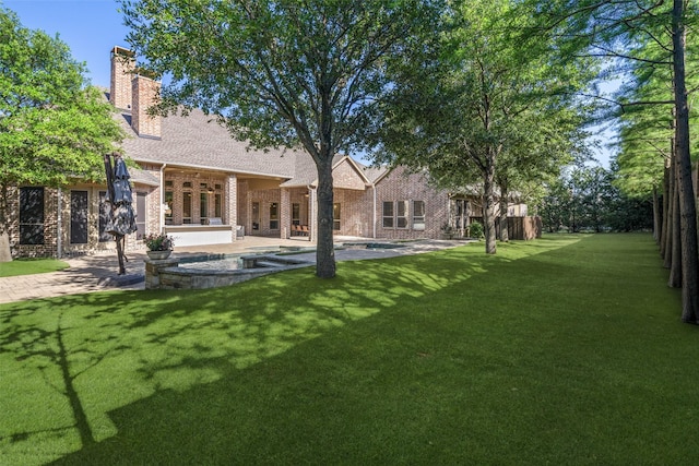 1861 Sand Creek Dr, Prosper, TX 75078 - rear view of property featuring brick siding, a lawn, a patio, a shingled roof, and a chimney