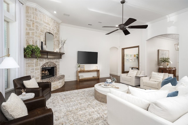 1861 Sand Creek Dr, Prosper, TX 75078 - living area featuring arched walkways, a ceiling fan, crown molding, wood finished floors, and a stone fireplace