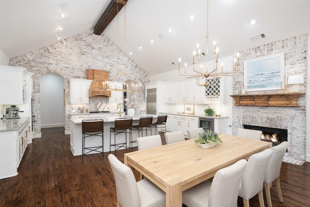 1861 Sand Creek Dr, Prosper, TX 75078 - dining room featuring beamed ceiling, a chandelier, dark wood-style floors, a glass covered fireplace, and beverage cooler