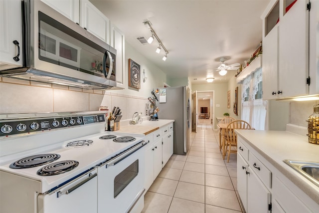 1102 Griffith Ave, Terrell, TX 75160 - kitchen with appliances with stainless steel finishes, light countertops, light tile patterned floors, and white cabinets