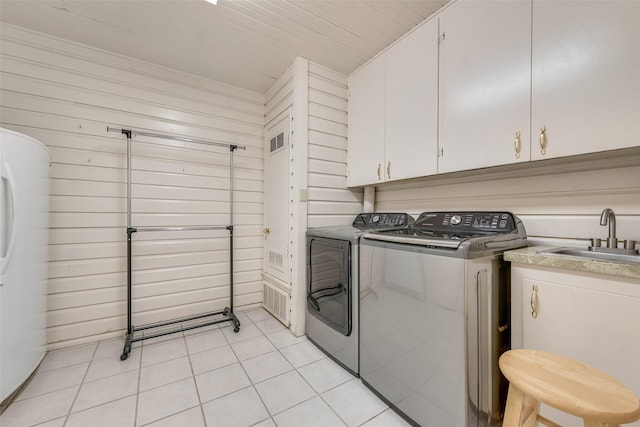 1102 Griffith Ave, Terrell, TX 75160 - washroom featuring washer and dryer, light tile patterned flooring, cabinet space, and wooden walls