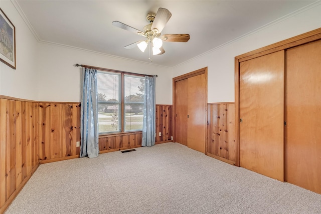 1102 Griffith Ave, Terrell, TX 75160 - unfurnished bedroom featuring a wainscoted wall, two closets, crown molding, wooden walls, and carpet flooring