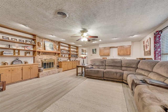 1102 Griffith Ave, Terrell, TX 75160 - living area with light wood-type flooring, a ceiling fan, a textured ceiling, a fireplace, and built in shelves