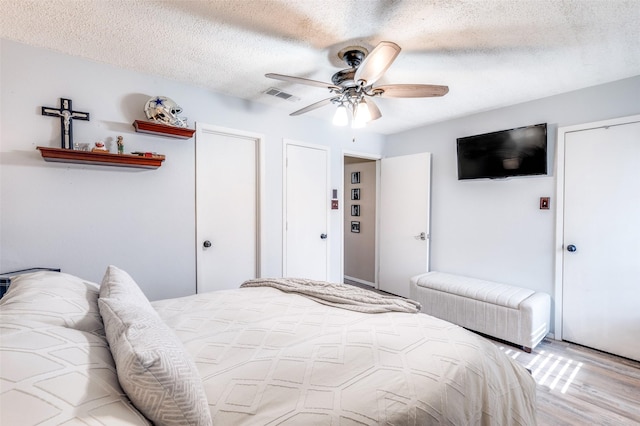 1161 Dallas Dr, Denton, TX 76205 - bedroom featuring light wood-type flooring, a textured ceiling, and ceiling fan