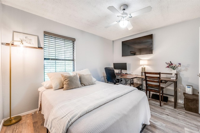 1161 Dallas Dr, Denton, TX 76205 - bedroom with light wood-type flooring, a textured ceiling, a desk, and ceiling fan