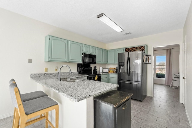 1512 La Paz Dr, Plano, TX 75074 - kitchen featuring black appliances, a peninsula, a breakfast bar, light stone countertops, and a textured ceiling