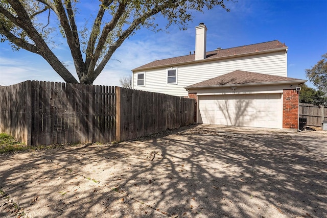 1512 La Paz Dr, Plano, TX 75074 - rear view of house with driveway, brick siding, an attached garage, and a chimney