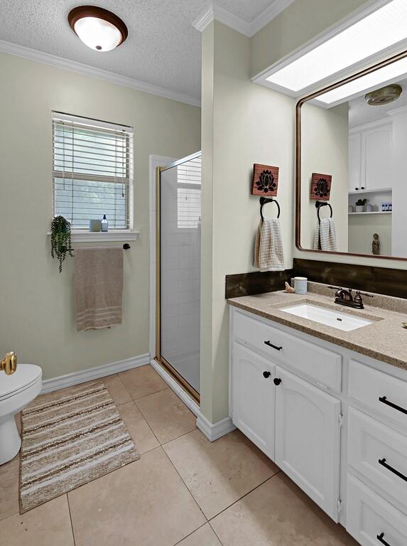 11001 Ridge Point Dr, Woodway, TX 76712 - full bath featuring vanity, a stall shower, crown molding, tile patterned flooring, and a textured ceiling