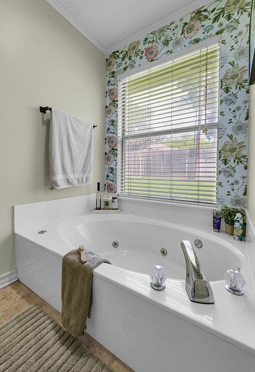 11001 Ridge Point Dr, Woodway, TX 76712 - bathroom featuring crown molding, a tub with jets, wallpapered walls, and a textured ceiling