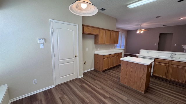 2217 Lone Pecan Dr, Garland, TX 75040 - kitchen with brown cabinetry, dark wood-style flooring, light countertops, a center island, and a textured ceiling
