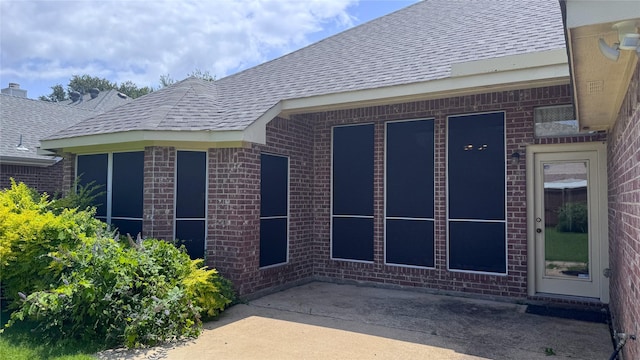 2217 Lone Pecan Dr, Garland, TX 75040 - view of exterior entry featuring brick siding, a shingled roof, and a patio area