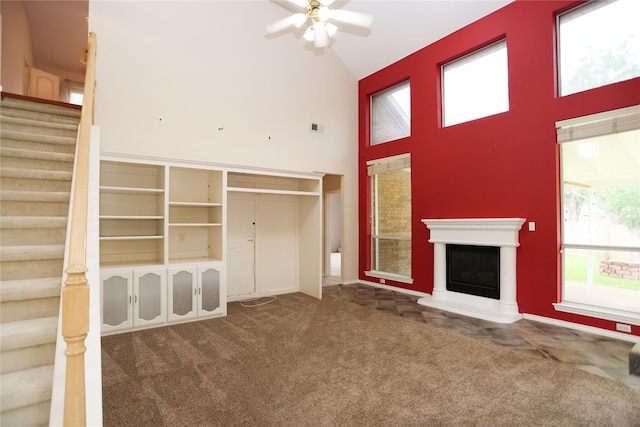 2325 Denham Dr, Arlington, TX 76001 - unfurnished living room with stairway, carpet flooring, a towering ceiling, ceiling fan, and a glass covered fireplace