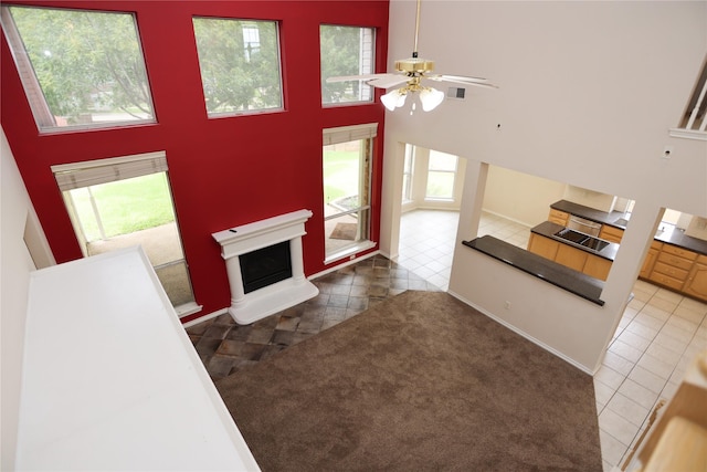 2325 Denham Dr, Arlington, TX 76001 - unfurnished living room featuring tile patterned flooring, a high ceiling, a fireplace with raised hearth, and a ceiling fan
