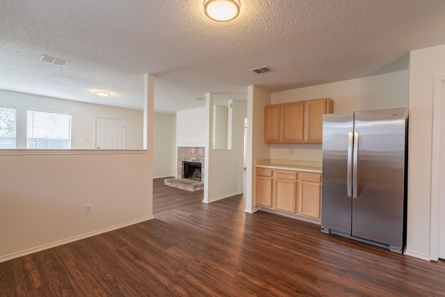 233 Stoneridge Dr, Mesquite, TX 75149 - kitchen featuring freestanding refrigerator, light brown cabinetry, dark wood finished floors, a textured ceiling, and a fireplace