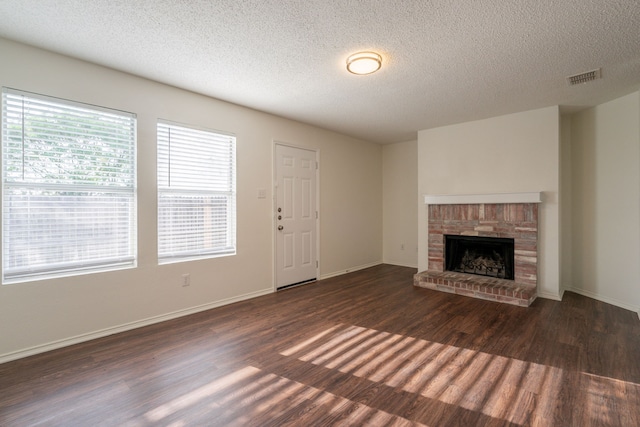 233 Stoneridge Dr, Mesquite, TX 75149 - unfurnished living room featuring dark wood finished floors, a textured ceiling, and a brick fireplace