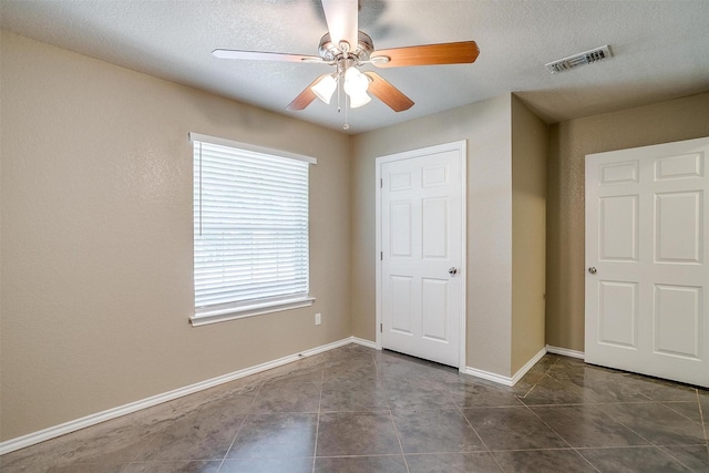 1414 Cheyenne Trl, Granbury, TX 76048 - unfurnished bedroom featuring ceiling fan, dark tile patterned floors, and a textured ceiling