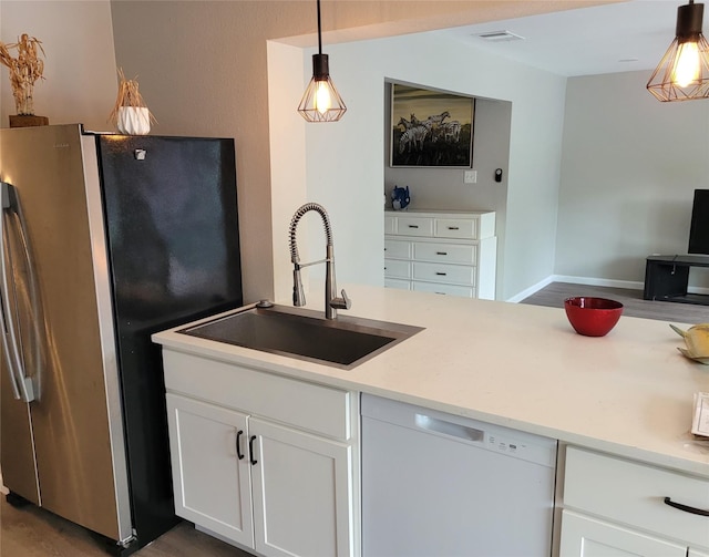 3309 Graybar Dr, Garland, TX 75040 - kitchen with freestanding refrigerator, white dishwasher, light countertops, hanging light fixtures, and white cabinetry