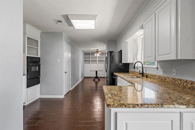 431 Brookwood Dr, Woodway, TX 76712 - kitchen with black oven, white cabinets, dark wood-type flooring, light stone countertops, and a warming drawer