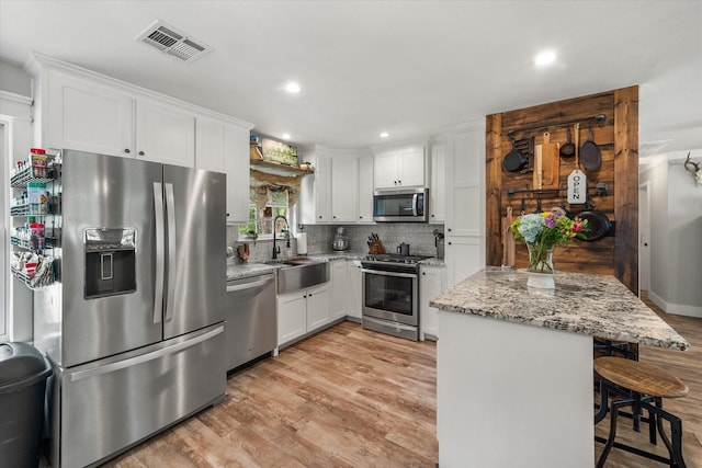 3121 SE County Road 2135, Corsicana, TX 75109 - kitchen with appliances with stainless steel finishes, backsplash, white cabinets, light stone counters, and light wood-type flooring