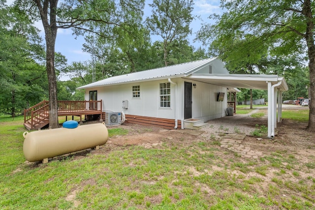 3121 SE County Road 2135, Corsicana, TX 75109 - back of property with a wooden deck, an attached carport, a metal roof, and a lawn