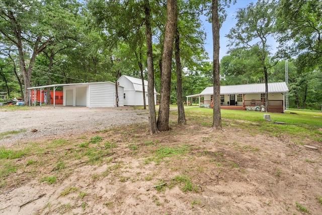 3121 SE County Road 2135, Corsicana, TX 75109 - view of yard featuring dirt driveway, view of wooded area, a porch, a detached carport, and an outbuilding