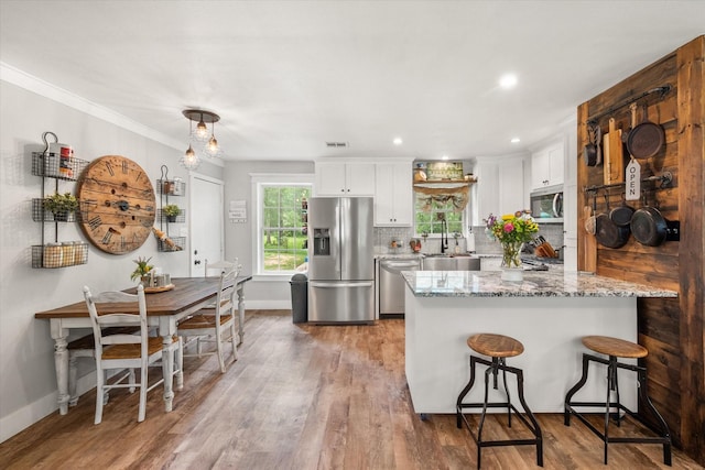 3121 SE County Road 2135, Corsicana, TX 75109 - kitchen with appliances with stainless steel finishes, a breakfast bar, white cabinetry, wood finished floors, and recessed lighting
