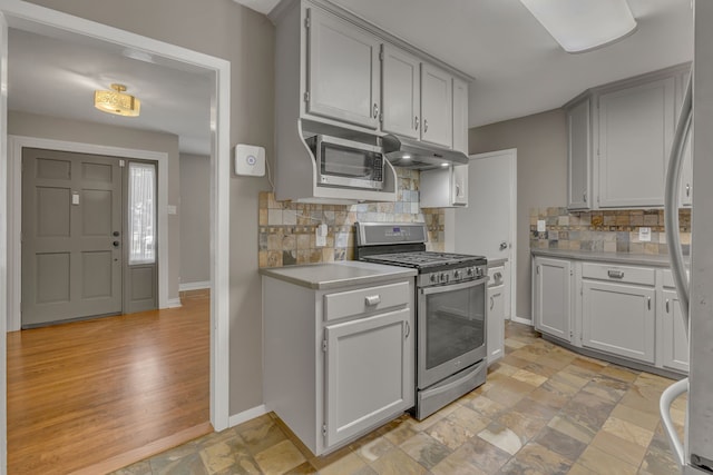 11502 Rupley Ln, Dallas, TX 75218 - kitchen featuring stainless steel appliances, light countertops, decorative backsplash, under cabinet range hood, and light stone finish flooring