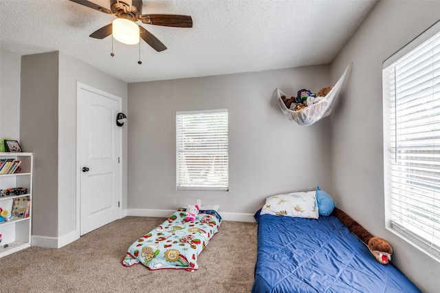 201 E Davis Ave, Alvarado, TX 76009 - carpeted bedroom featuring multiple windows, a textured ceiling, and a ceiling fan
