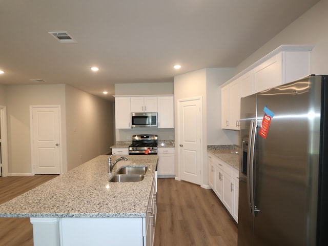453 Forsyth Dr, Princeton, TX 75407 - kitchen with stainless steel appliances, wood finished floors, white cabinetry, recessed lighting, and a kitchen island with sink