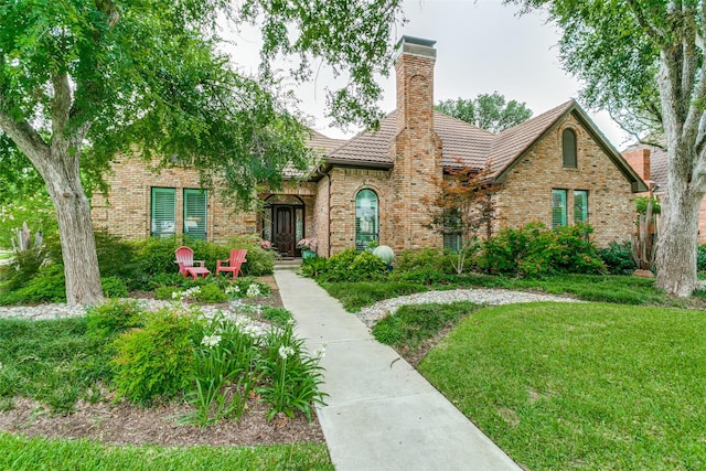 1600 Crockett Cir, Irving, TX 75038 - tudor home featuring a chimney, brick siding, a front lawn, and a tiled roof