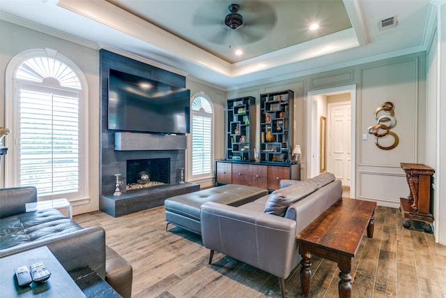 1600 Crockett Cir, Irving, TX 75038 - living area featuring a tray ceiling, a ceiling fan, wood finished floors, crown molding, and a large fireplace