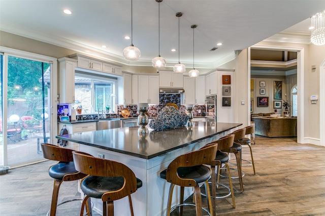 1600 Crockett Cir, Irving, TX 75038 - kitchen with crown molding, dark countertops, oven, white cabinets, and a kitchen bar