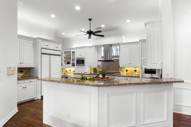 3928 Dove Creek Ln, Plano, TX 75093 - kitchen with wall chimney exhaust hood, a ceiling fan, tasteful backsplash, white cabinets, and built in appliances