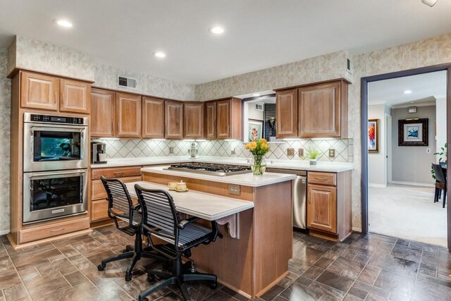 5715 Northaven Rd, Dallas, TX 75230 - kitchen featuring stainless steel appliances, light countertops, a kitchen island, recessed lighting, and a kitchen bar