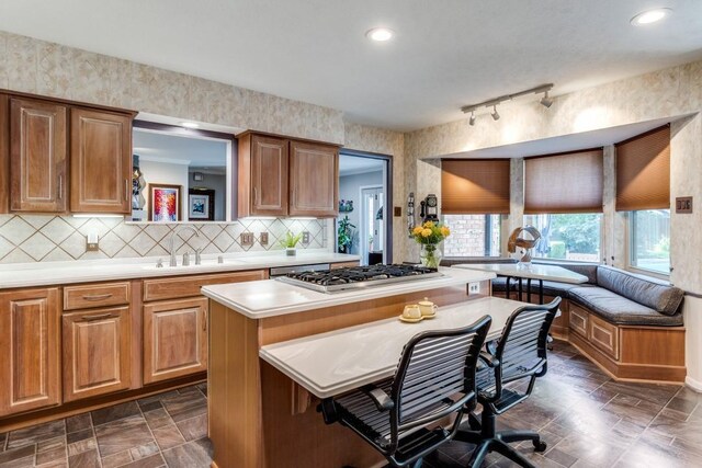 5715 Northaven Rd, Dallas, TX 75230 - kitchen with stainless steel gas cooktop, light countertops, tasteful backsplash, a breakfast bar area, and a kitchen island