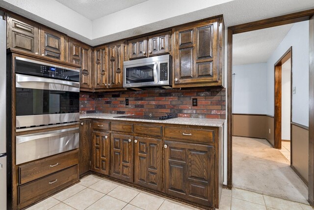 2214 Parkside Dr, Denton, TX 76201 - kitchen featuring appliances with stainless steel finishes, a warming drawer, light tile patterned floors, light countertops, and a textured ceiling