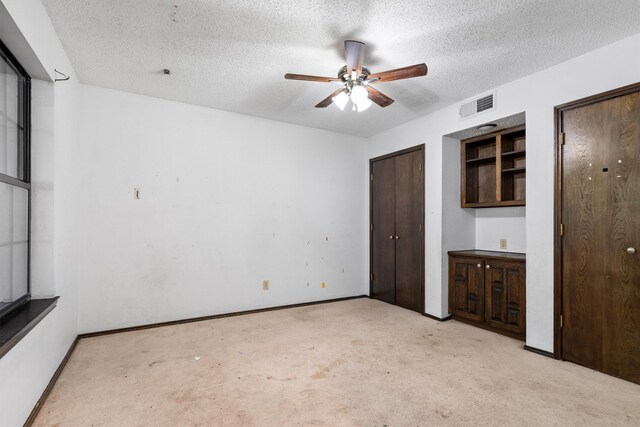 2214 Parkside Dr, Denton, TX 76201 - unfurnished bedroom with light colored carpet, a textured ceiling, multiple closets, and ceiling fan