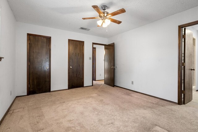 2214 Parkside Dr, Denton, TX 76201 - unfurnished bedroom featuring carpet floors, multiple closets, a textured ceiling, and ceiling fan