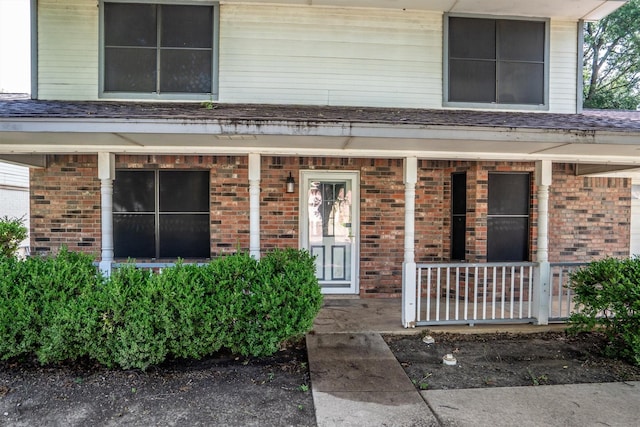 2214 Parkside Dr, Denton, TX 76201 - property entrance featuring a porch, brick siding, and a shingled roof
