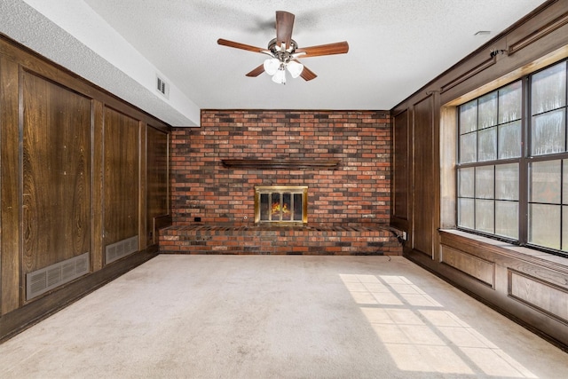 2214 Parkside Dr, Denton, TX 76201 - unfurnished living room with a brick fireplace, brick wall, a ceiling fan, a textured ceiling, and wooden walls