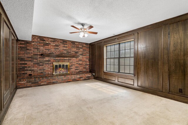 2214 Parkside Dr, Denton, TX 76201 - unfurnished living room with a brick fireplace, ceiling fan, brick wall, a textured ceiling, and wood walls