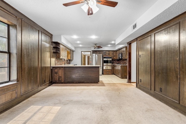 2214 Parkside Dr, Denton, TX 76201 - kitchen with ceiling fan, appliances with stainless steel finishes, light carpet, open shelves, and a peninsula
