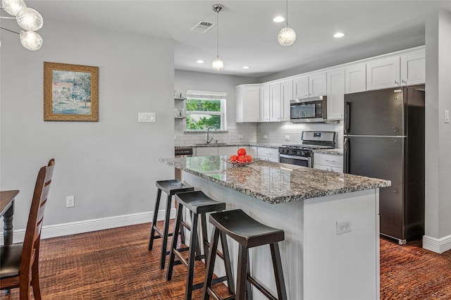 2711 El Tivoli Dr, Dallas, TX 75211 - kitchen featuring stainless steel appliances, tasteful backsplash, a kitchen island, dark wood-type flooring, and white cabinetry