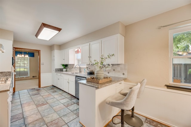 13861 Far Hills Ln, Dallas, TX 75240 - kitchen featuring white cabinets, backsplash, a peninsula, stainless steel dishwasher, and a kitchen bar